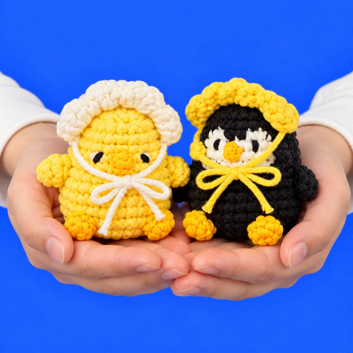 Pia & Paco — Poussin et pingouin avec bonnets au crochet — présentation en main.