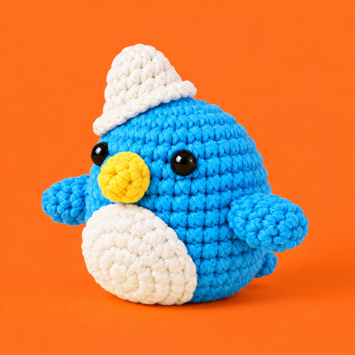 Colin — Pingouin bleu à bonnet blanc au crochet — vue de trois quarts.